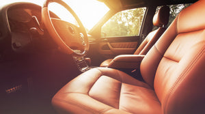 Brown leather car seats with sunlight shining through the windscreen