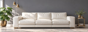 White leather sofa in a contemporary living room with a grey wall and brass accents.