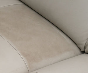 A close-up view of a light beige leather or faux-leather sofa seat cushion with visible dust and dirt marks on the left panel.
