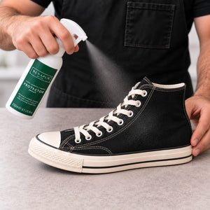 Spraying Renapur Suede & Fabric Protector over the upper of a black canvas trainer.