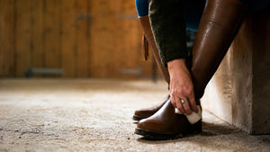 Applying Renapur Leather Balsam to brown leather boots using an application sponge