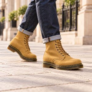 Man walking in yellow suede lace-up boots and turned-up jeans.