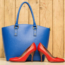 Blue handbag and red leather shoes against a wooden background.