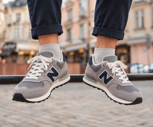 Man wearing grey suede and mesh trainers with navy trousers.