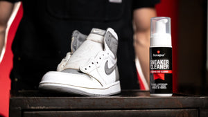 White leather high-top trainer beside a bottle of Renapur Sneaker Cleaner.